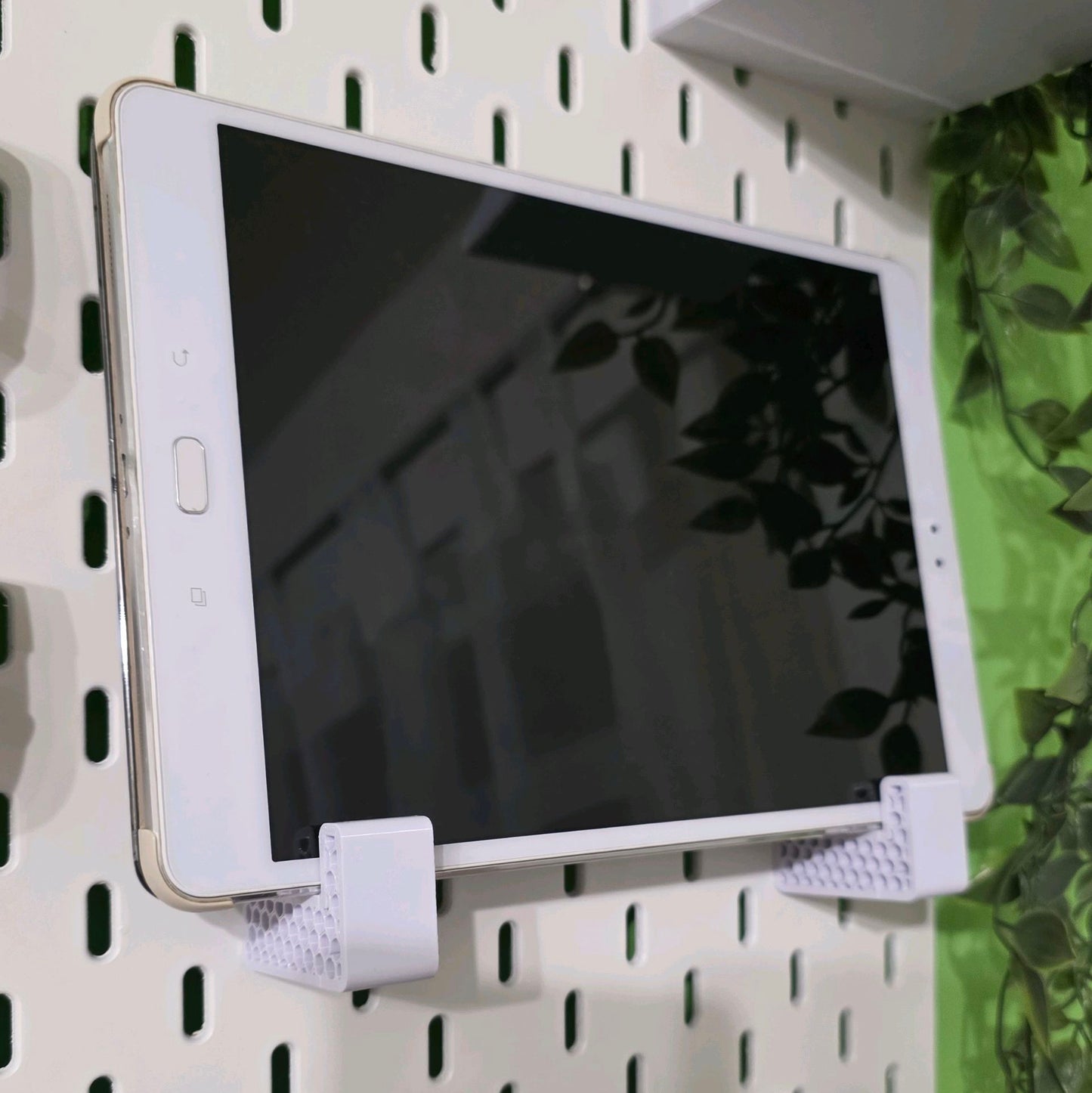 White tablet on a pegboard with headphones below