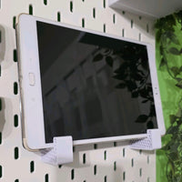 White tablet on a pegboard with headphones below