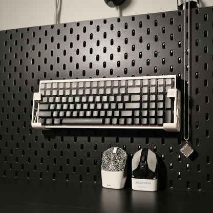 Mechanical keyboard on a black pegboard with tools below